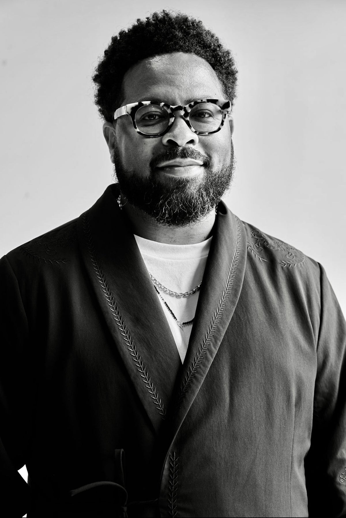 Black and white portrait of Kendall Hurns wearing glasses and a dark jacket.